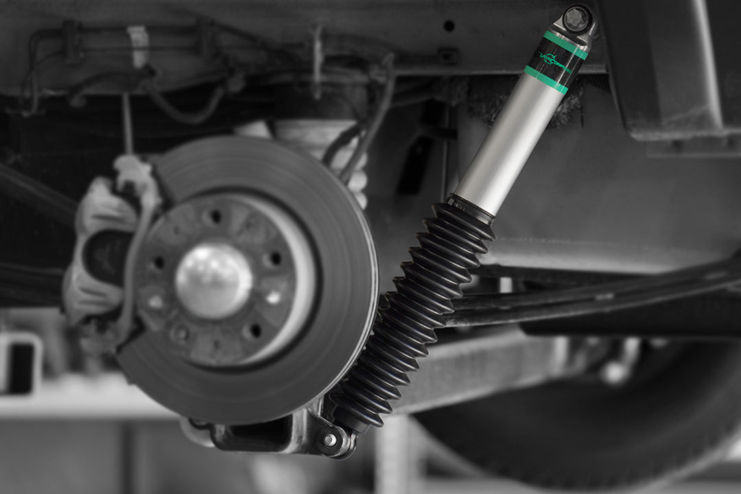 Close-up of a vehicle's suspension system with a focus on the shock absorber and wheel.