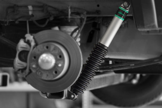 Close-up of a vehicle's suspension system with a focus on the shock absorber and wheel.