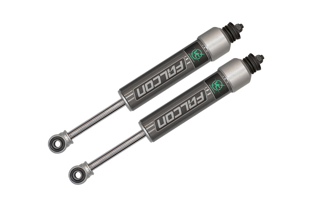 Pair of Falcon 2.1 monotube front shocks for Sprinter 4x4, featuring black rubber caps and grey cylinders, designed by Van Compass for improved vehicle handling.