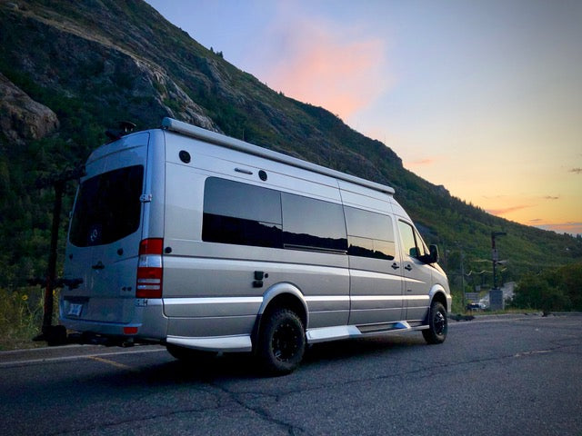 Silver van equipped with VAN COMPASS STAGE 3 OPTI-RATE DUALLY SYSTEM - SPRINTER AWD, 4X4 (2019-PRESENT 3500), parked on roadside, showcasing advanced suspension upgrades.