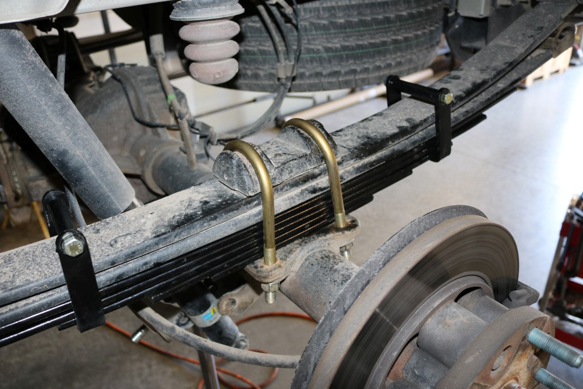 Close-up of the REAR 5 LEAF MINI SPRING PACK for 2015+ Ford Transit, showcasing metal construction and detailed components for improved ride quality and stability.