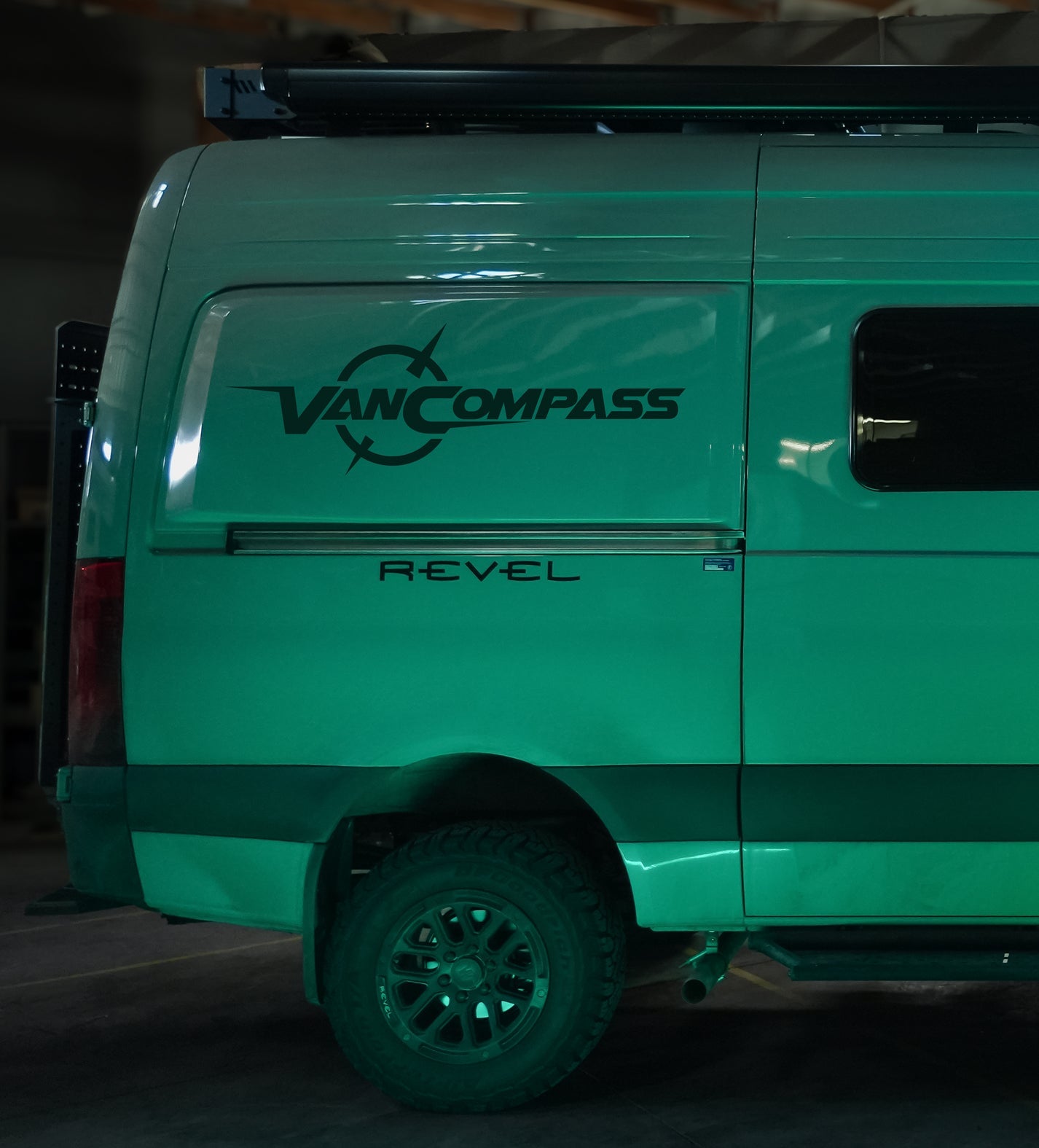 A white van parked on a rocky surface with visible close-ups of its black tire, yellow light, logo, and headlight.