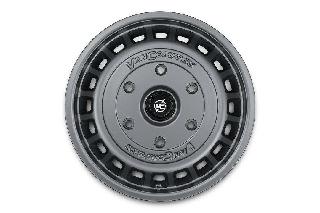 A dark gray metallic Van Compass wheel, shown from a top-down perspective on a solid white background.
