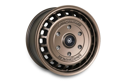A single metallic bronze-colored van wheel rim with a multi-spoke design and cutouts, featuring the 'Van Compass' brand name and logo embossed on the center cap, set against a plain white background.