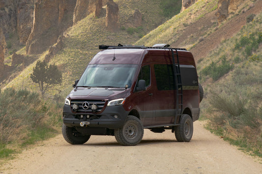STRIKER AWD 2 Lift Kit for 2023+ Sprinter AWD, shown on a red van parked on a dirt road, enhances ground clearance and tire traction for improved off-road performance.